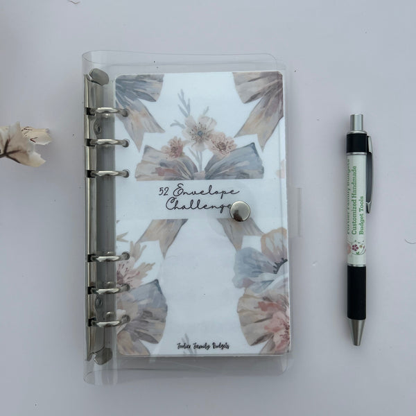 Notebook with floral design on a white surface with a pen next to it
