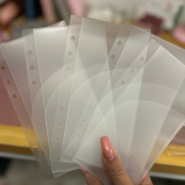 Hand holding a set of clear plastic pages with holes on a blurred background