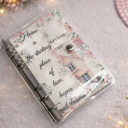 Decorative notebook with floral design and text on a soft surface with lights and flowers.