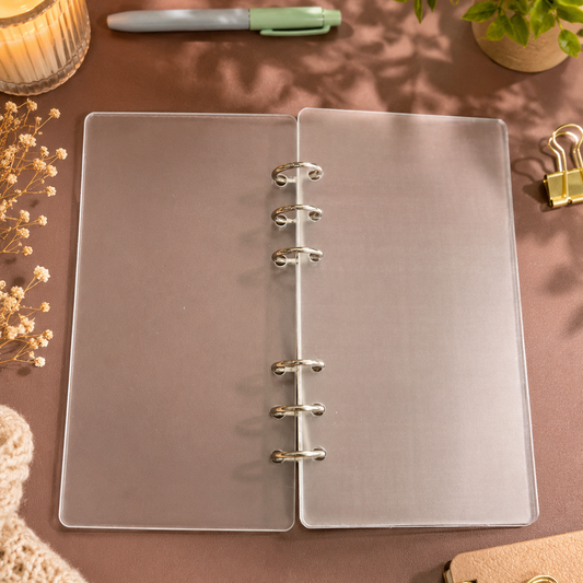 Clear planner on a desk with a candle, pen, and plant