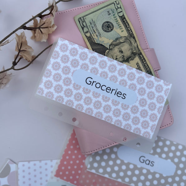 aesthetic pink and neutral A6 cash envelopes labeled Groceries, Gas and Target, styled with a pink binder, $20 bill and floral decor.