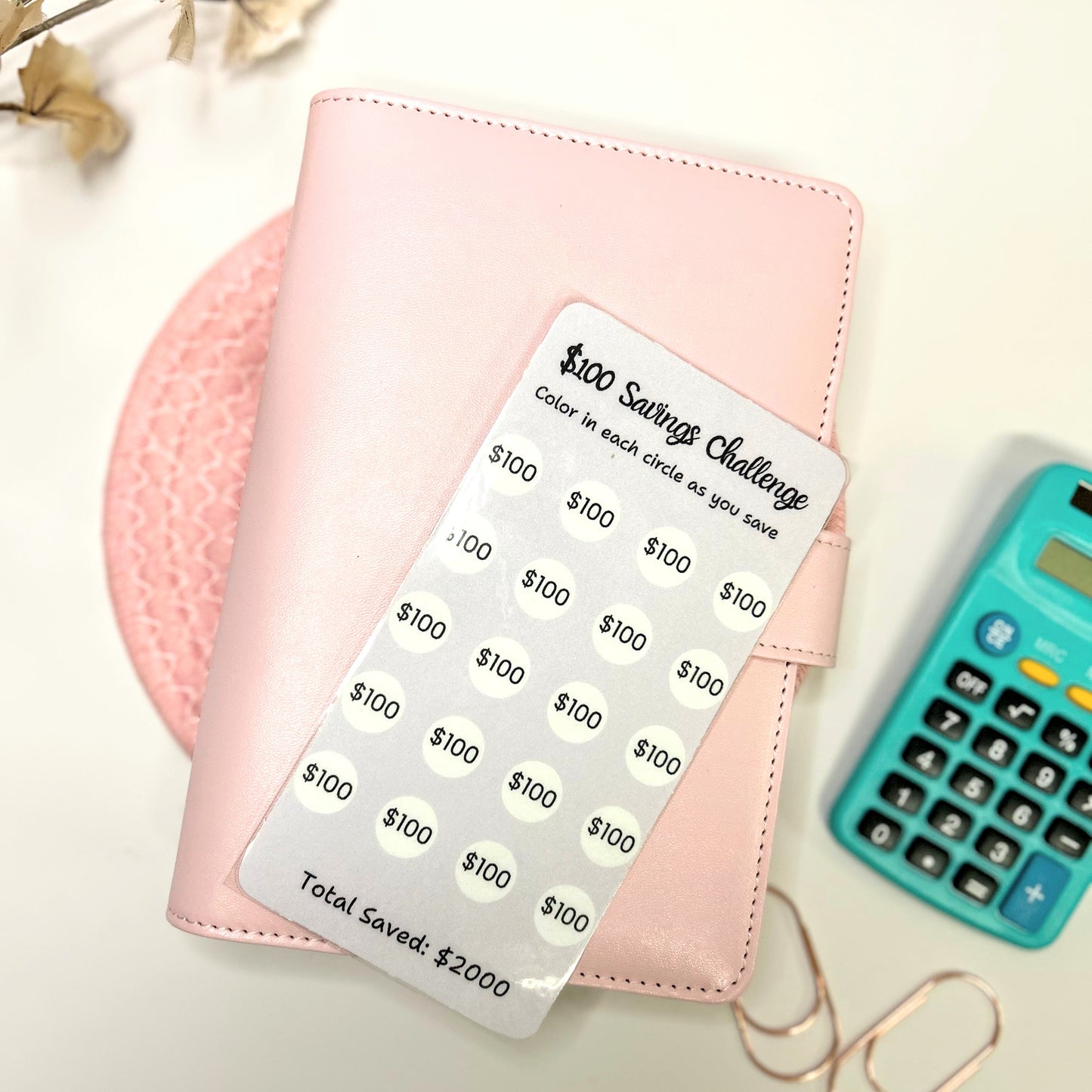 Pink wallet with money-saving stickers and a calculator on a light background
