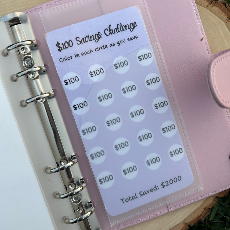 Pink planner with money tracking stickers on a wooden surface