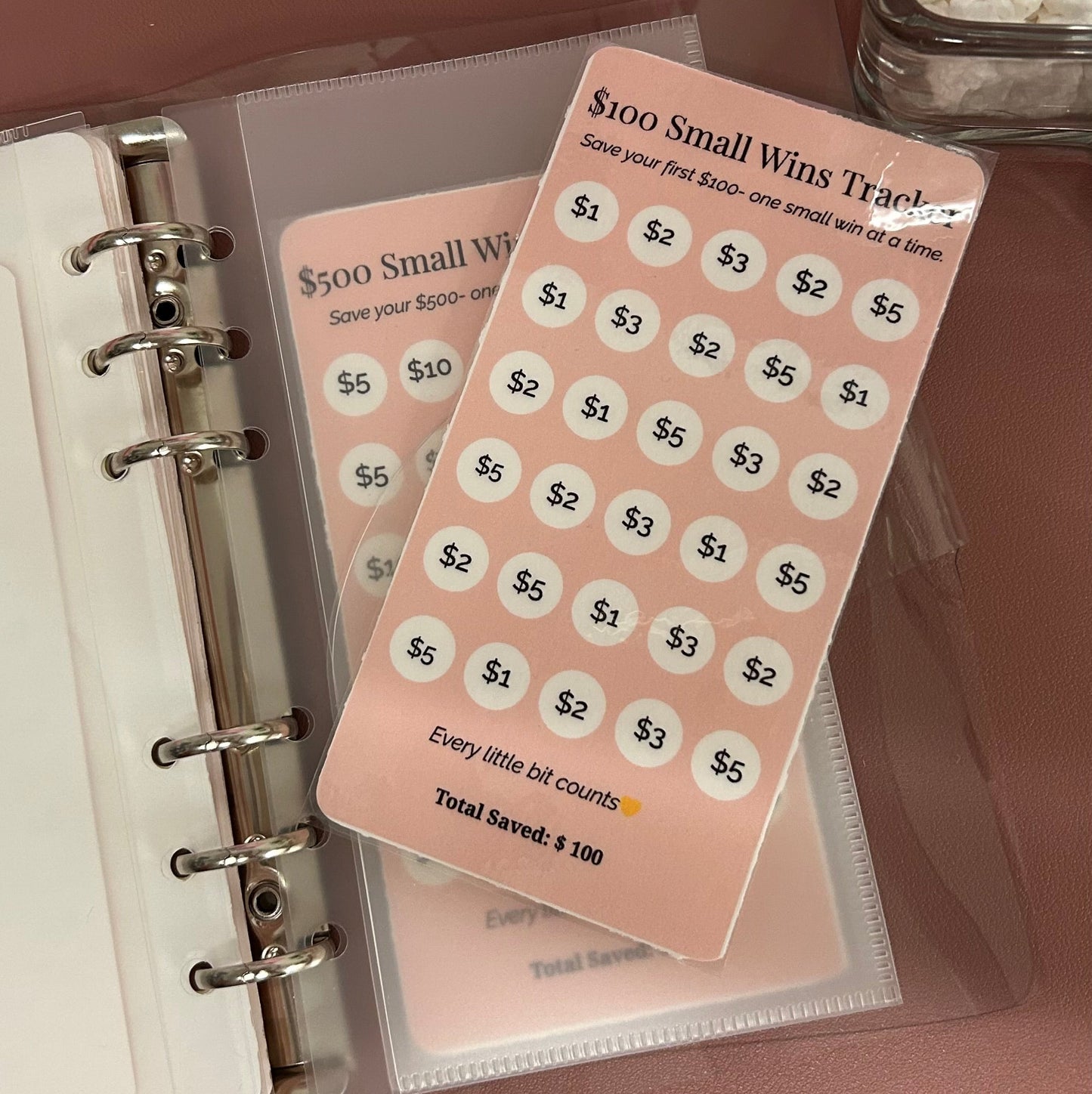 Small white cards with black text on a pink background inside a planner.