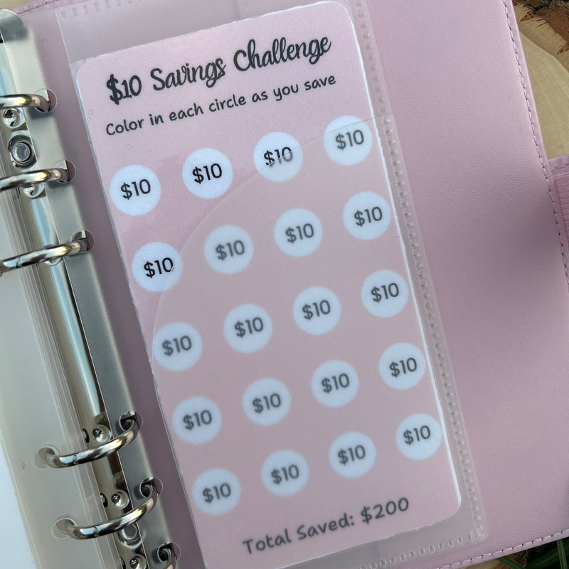 Pink savings challenge tracker with circular stickers on a wooden surface