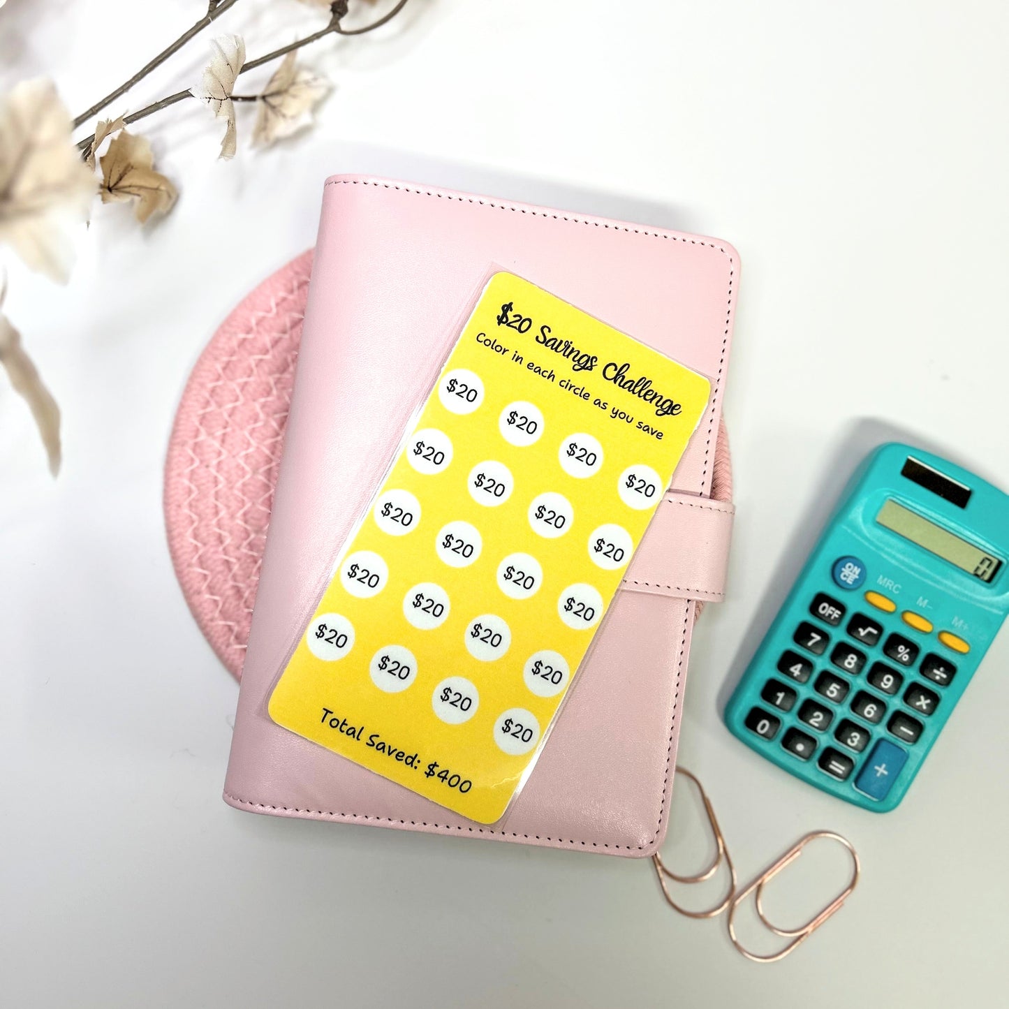 Pink savings tracker with yellow savings challenge card and teal calculator on a light surface.