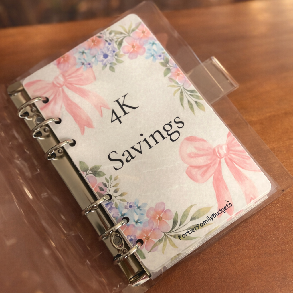 Small notebook with floral design and '4K Savings' text on a wooden surface