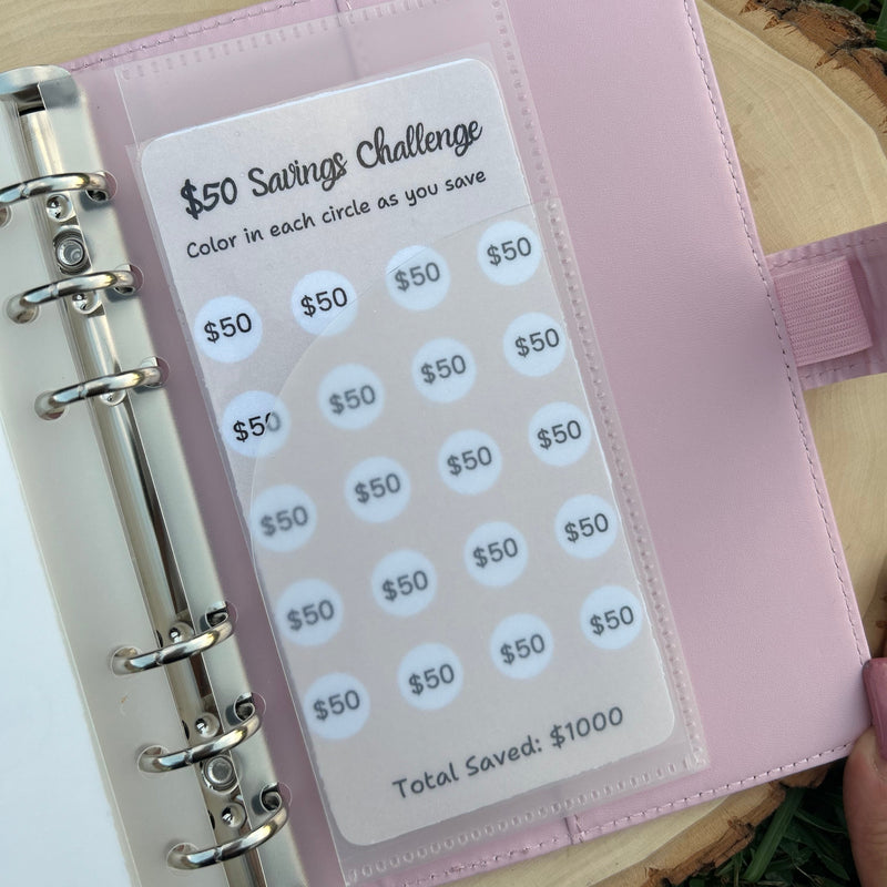 Pink savings challenge planner on a wooden surface with grass in the background