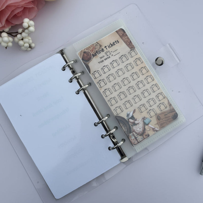 Open planner with decorative insert on a light surface with flowers and a pen.