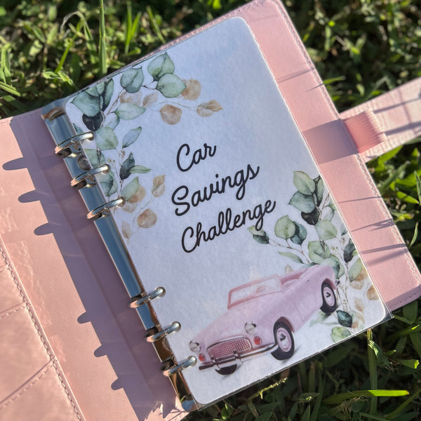 Notebook with 'Car Savings Challenge' on a grass background