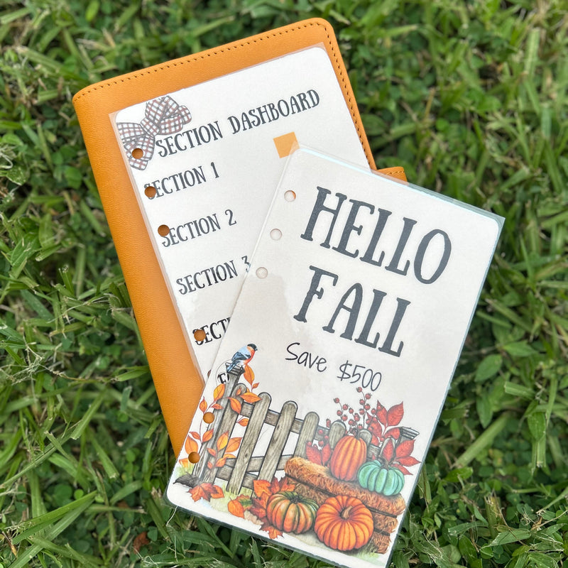 Two planner accessories on grass, one with 'Hello Fall' design and the other with a dashboard layout.