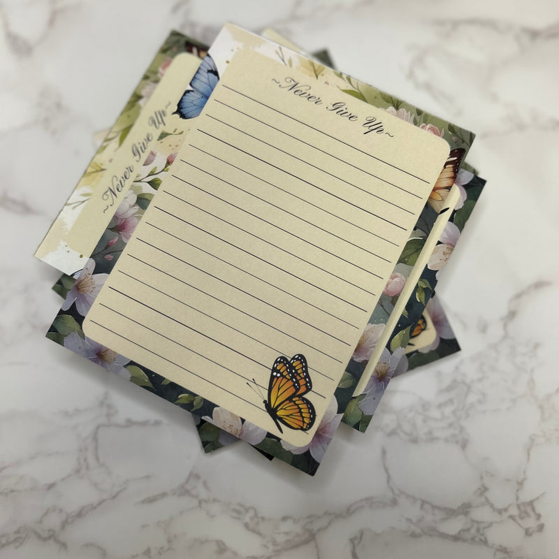 Set of decorative notepads with butterfly designs on a marble surface
