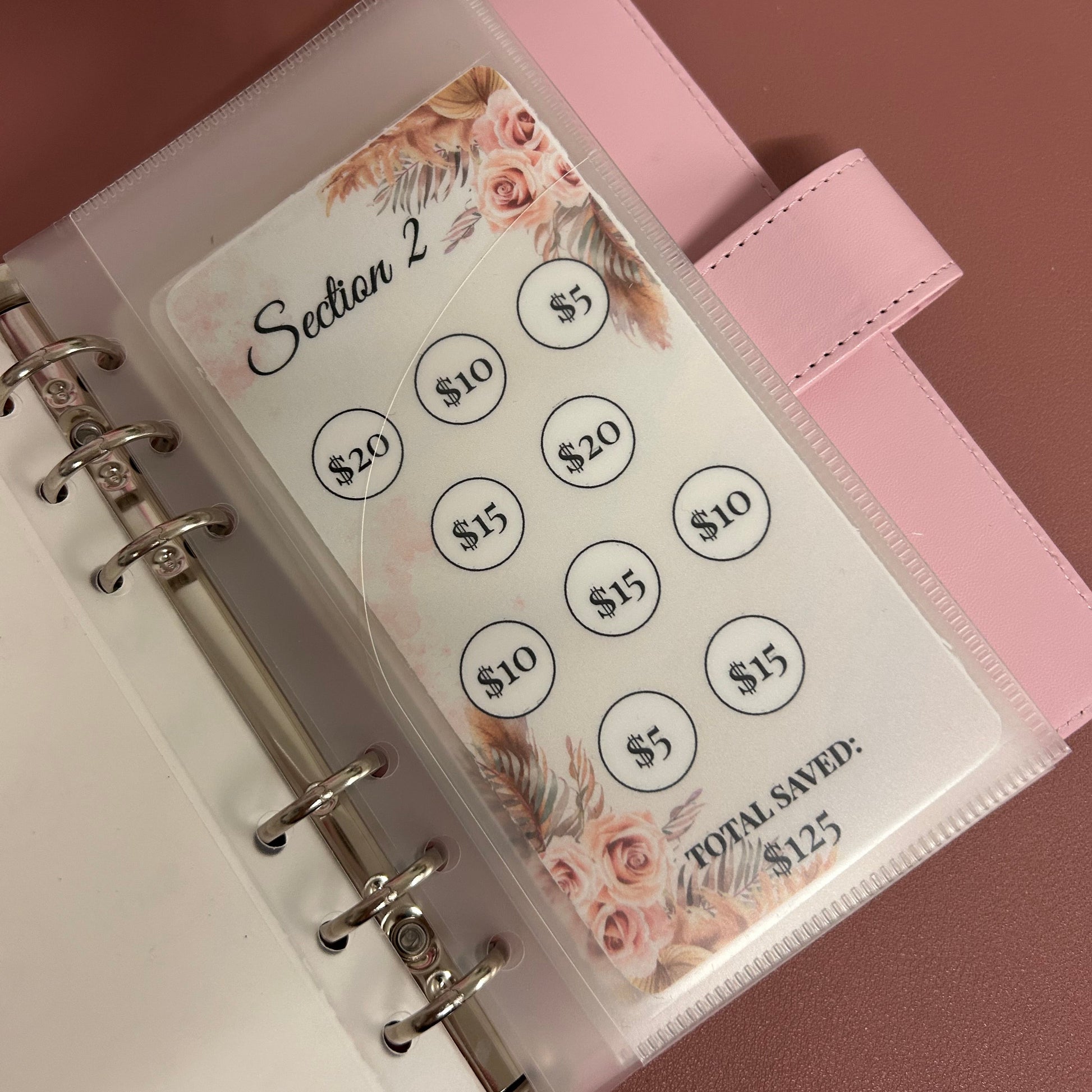 Pink planner with floral design and circular stickers on a matching pink background