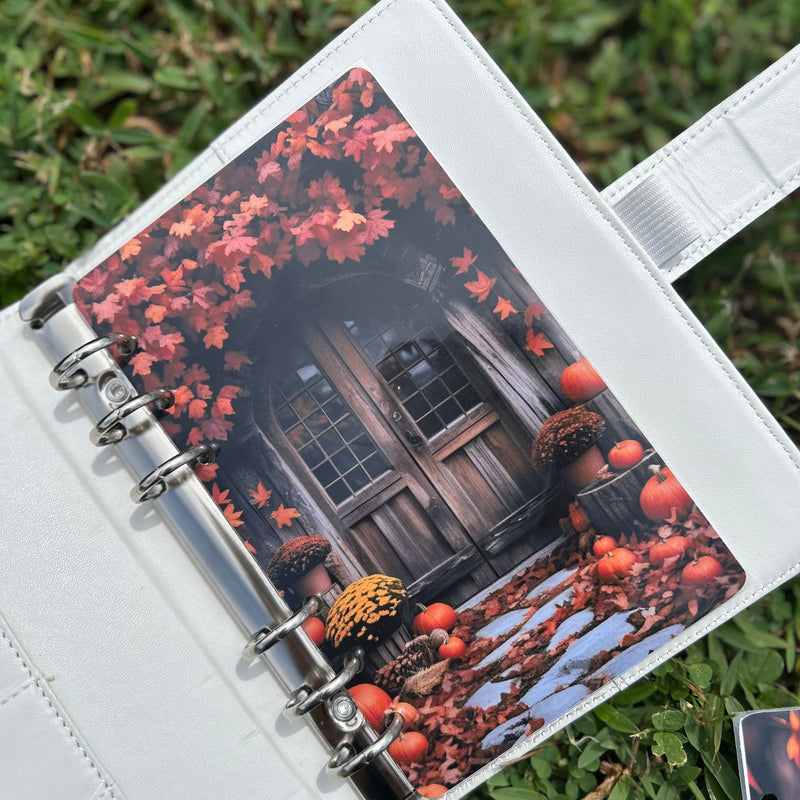 Planner with a fall-themed cover featuring pumpkins and leaves on grass