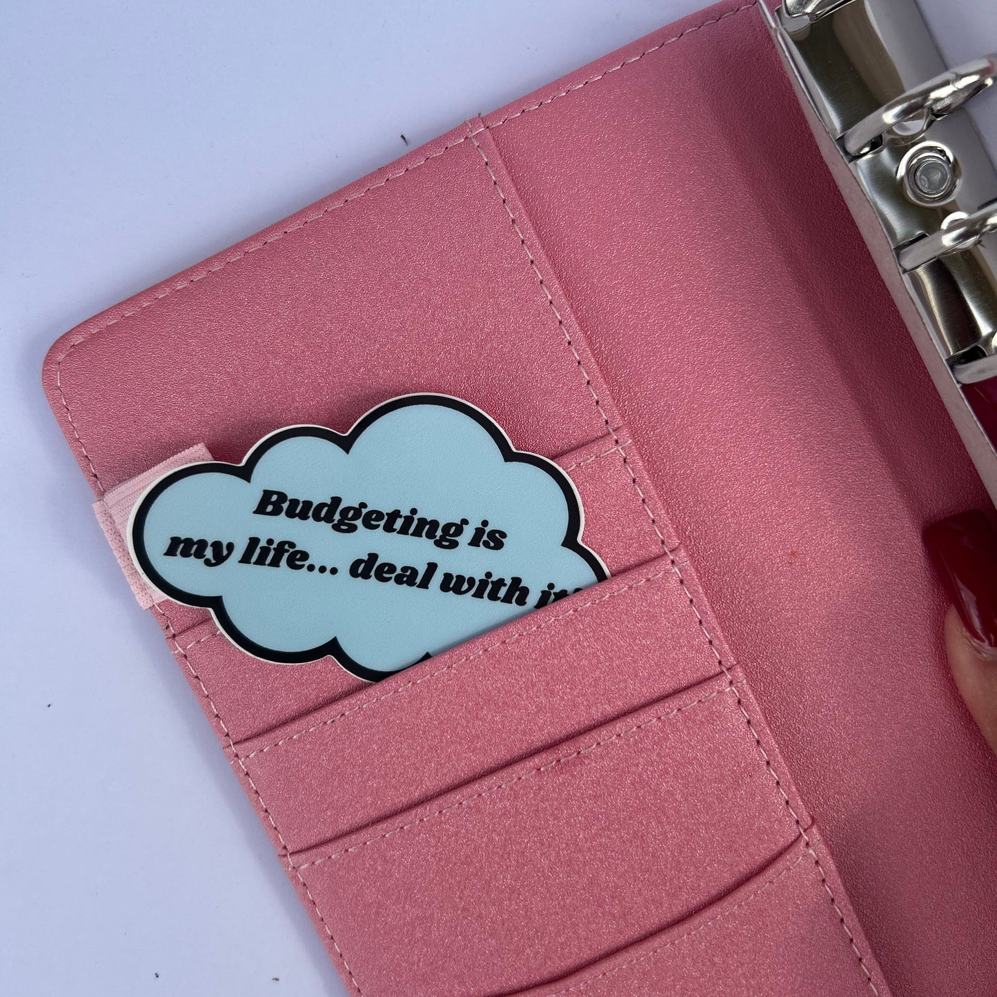 Pink wallet with a decorative tag inside, featuring text.