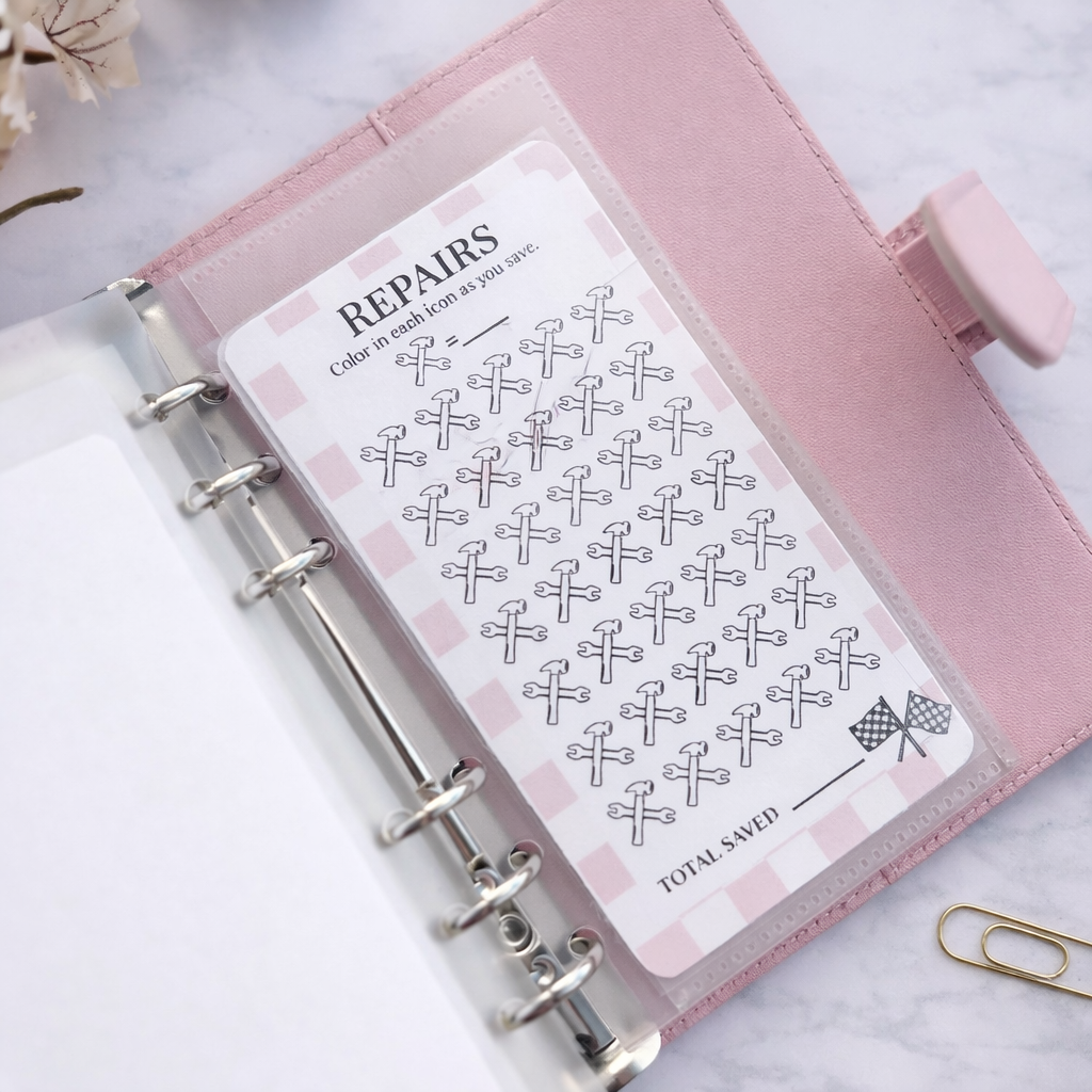 Pink planner with a repair tracking sheet on a marble surface