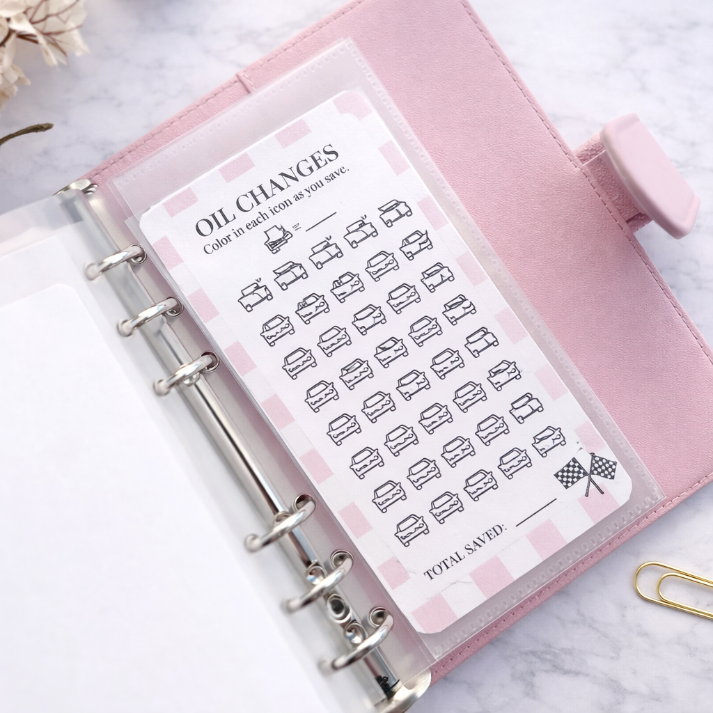 Pink planner with oil change tracker sticker on a marble surface