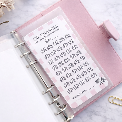 Pink planner with oil change tracker sticker on a marble surface