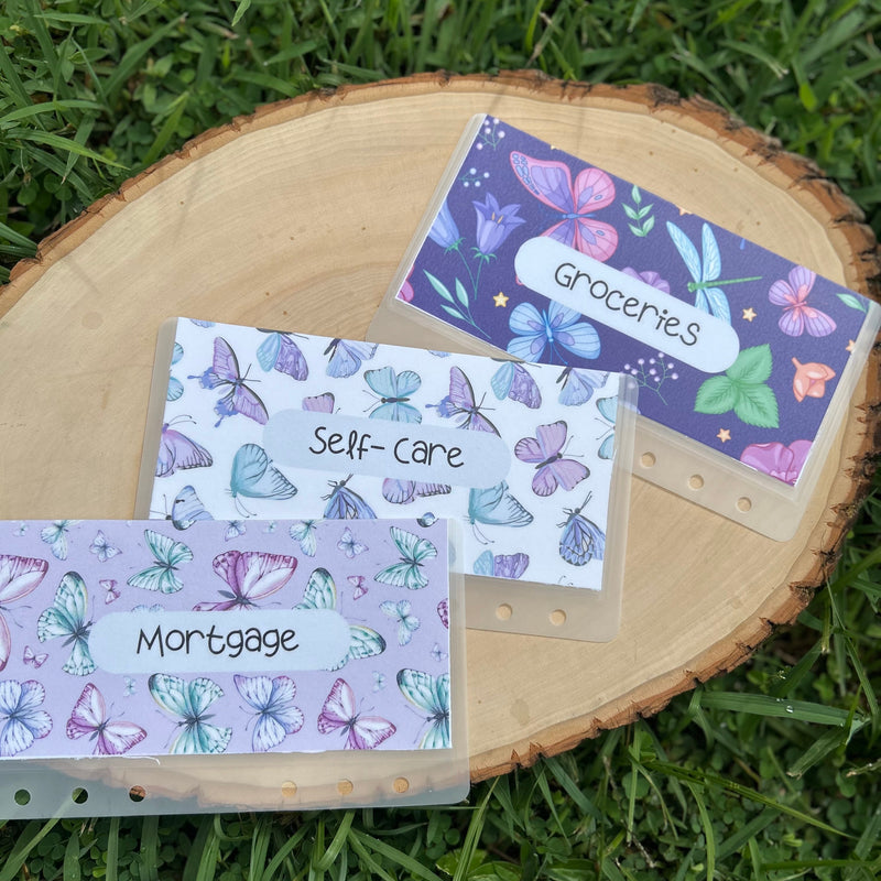 Three labeled cash envelopes with butterfly designs on a grass background