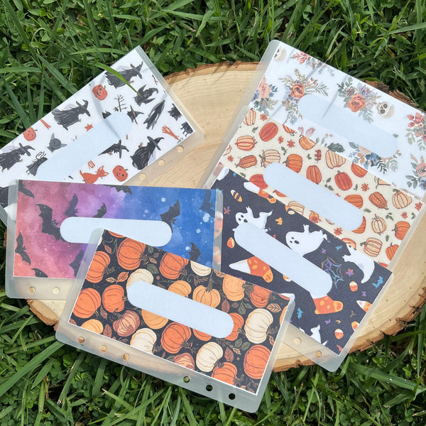 Four small books with Halloween-themed covers on a wooden surface outdoors.