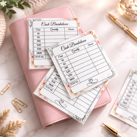 Cash breakdown sheets on a pink notebook with decorative elements on a marble surface.