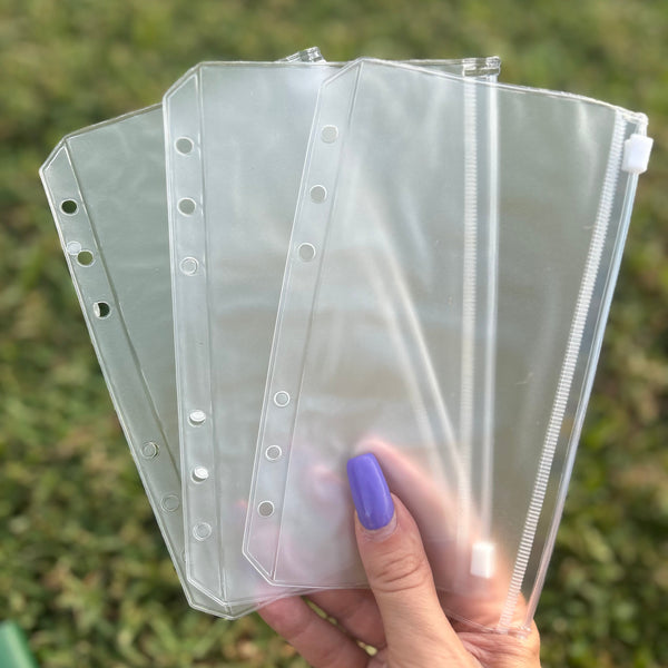 Clear plastic sleeves with holes held by a hand against a grassy background