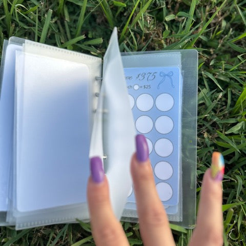 Hand holding a clear plastic case with circular components on grass