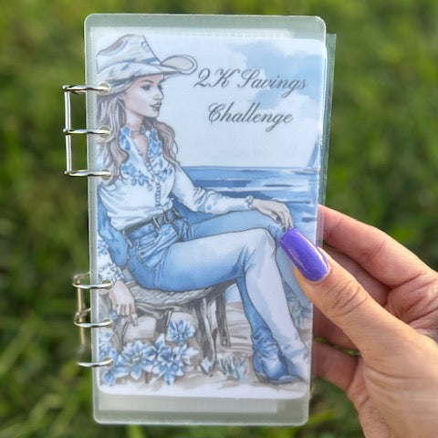 Planner with a design of a person in a cowboy hat and blue outfit, held against a grassy background.