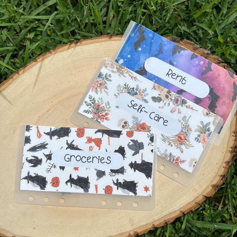 Set of four labeled cash envelopes on a wooden surface with grass in the background
