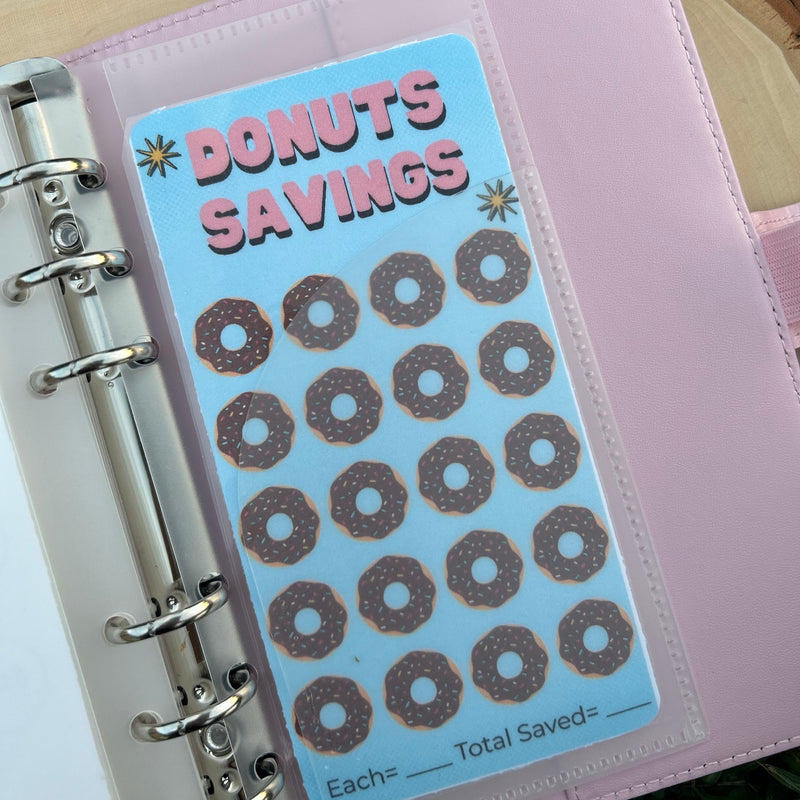 Pink planner with 'Donuts Savings' stickers on a grass background