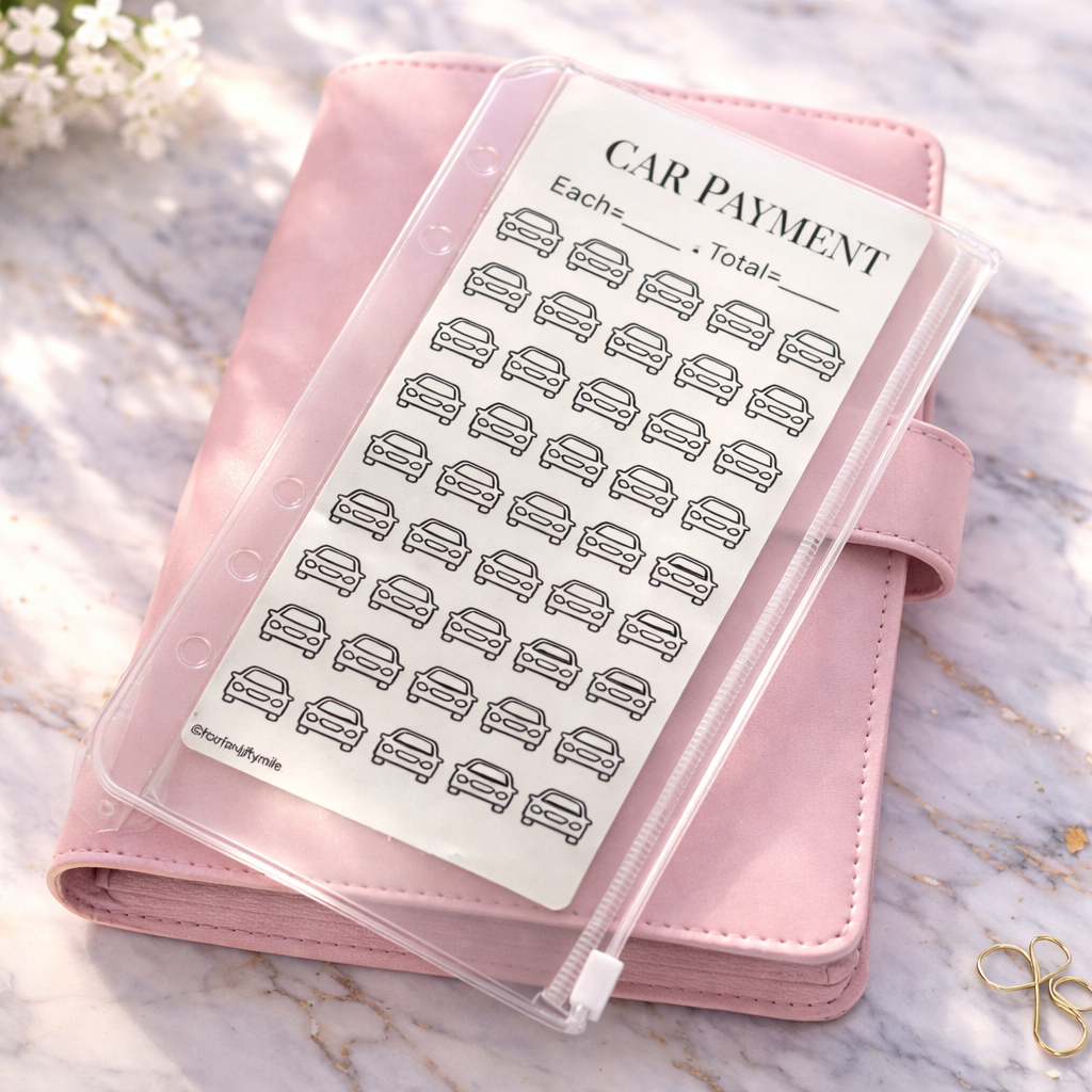 Pink planner with a clear sleeve featuring car payment tracker on a marble surface.