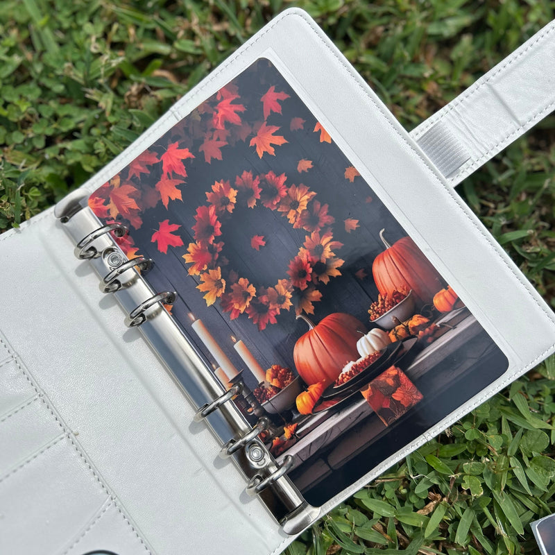 Planner with autumn design on cover, placed on grass