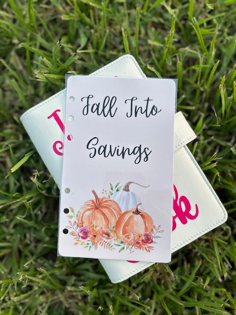 Notebook with 'Fall Into Savings' design on grass