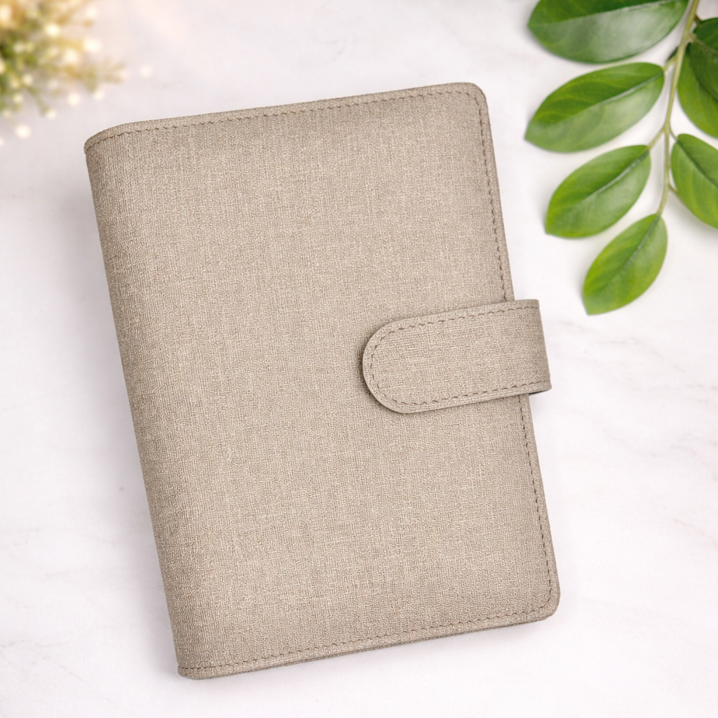 Beige planner on a white surface with green leaves in the background
