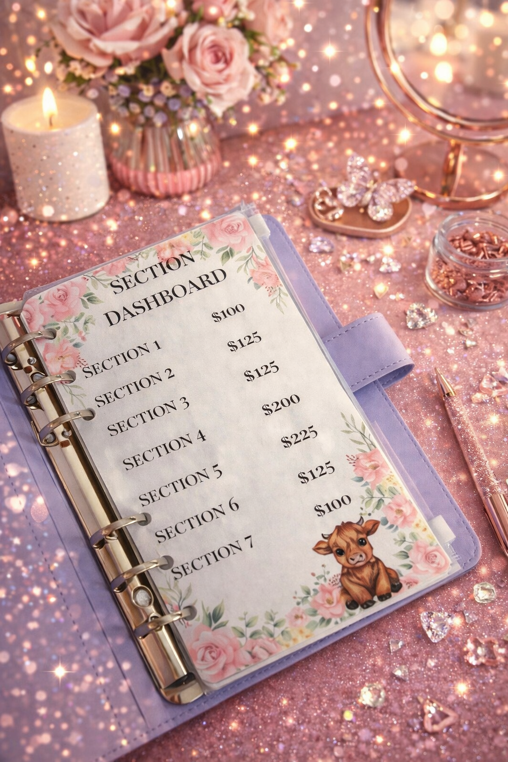 Planner with floral design on a glittery surface with candles and flowers.