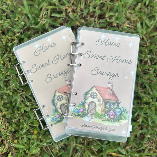 Two 'Home Sweet Home Savings' binders on grass