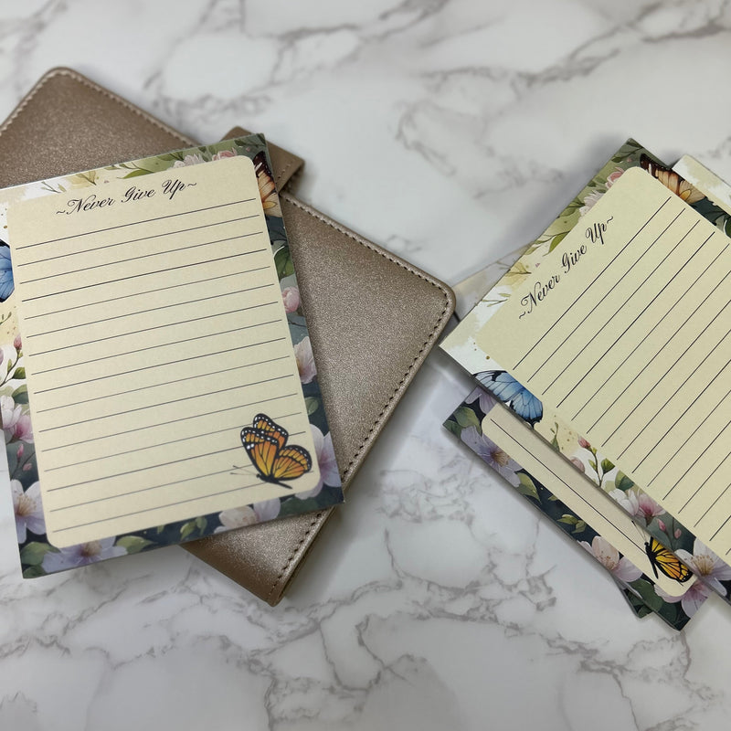 Notebooks with floral designs and motivational text on a marble surface