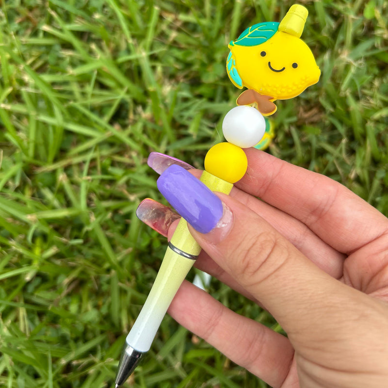 Hand holding a pen with a cartoon character on a grassy background
