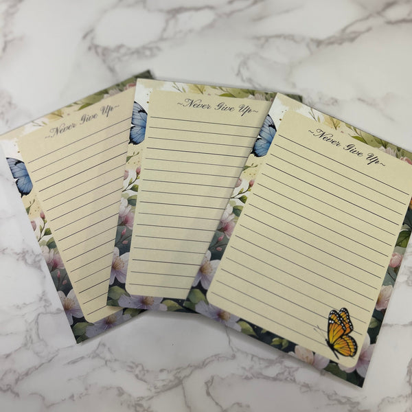 Three lined notepads with butterfly designs on a marble surface