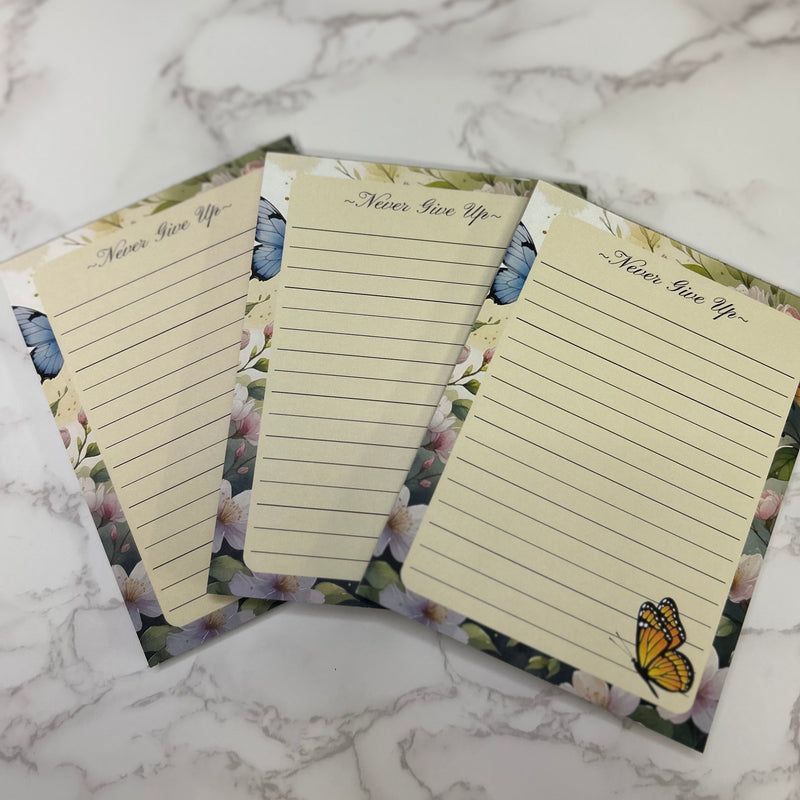 Three lined notepads with butterfly designs on a marble surface