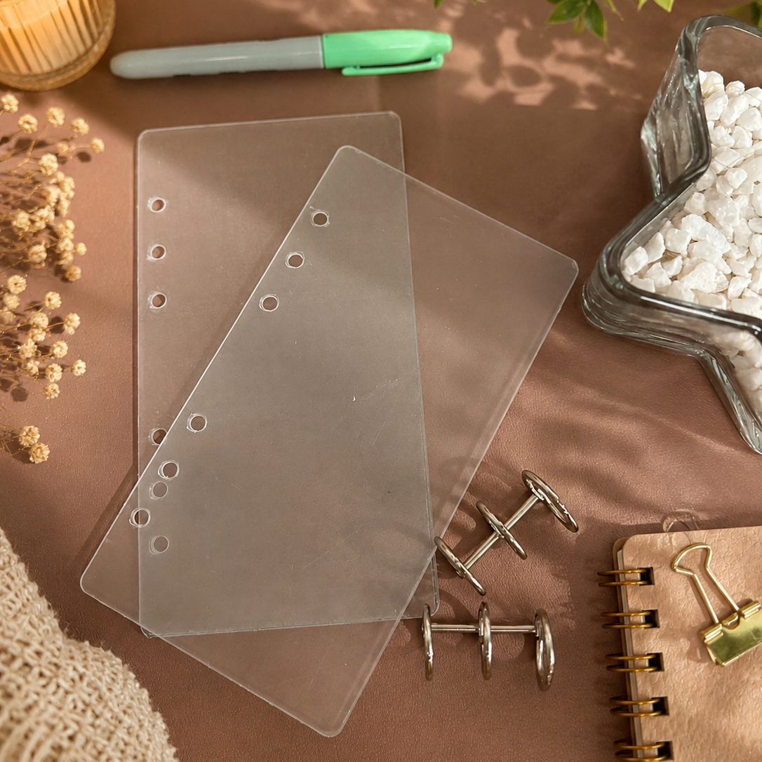 Clear plastic cards on a brown surface with a candle, pen, and decorative items.
