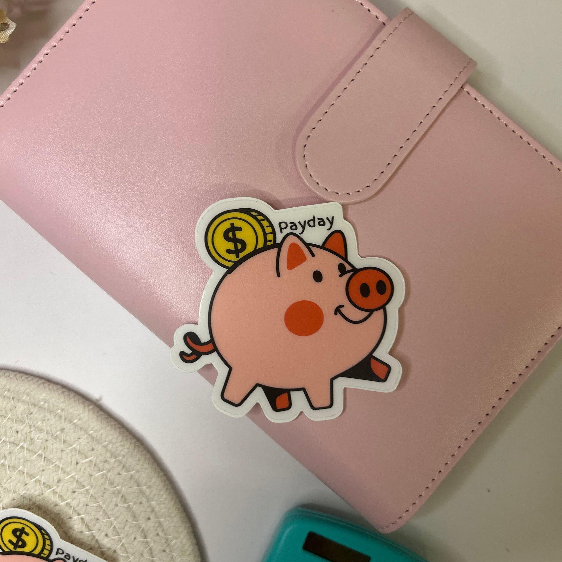 Pink notebook with a cartoon sticker of a pig on a white surface