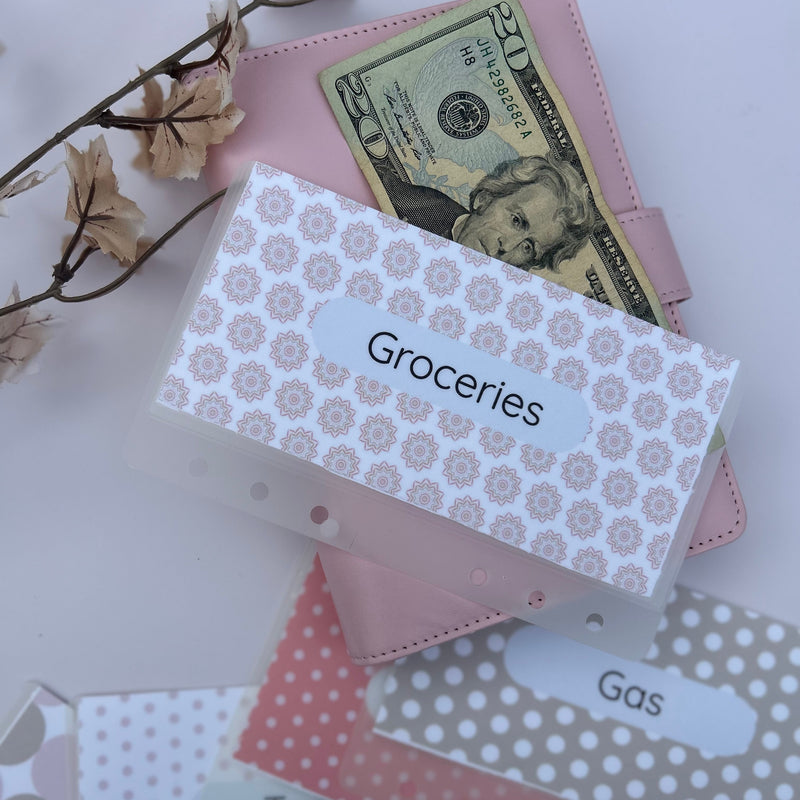 aesthetic pink and neutral A6 cash envelopes labeled Groceries, Gas and Target, styled with a pink binder, $20 bill and floral decor. 