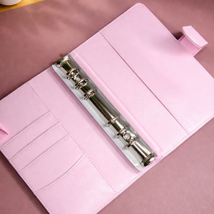 Pink planner with a metal ring on a pink surface