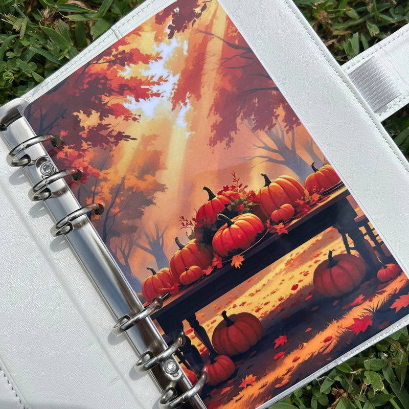 Notebook with a pumpkin patch design on the cover, placed on grass.
