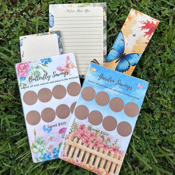 Collection of stationery items including a notepad, stickers, and a bookmark on grass.