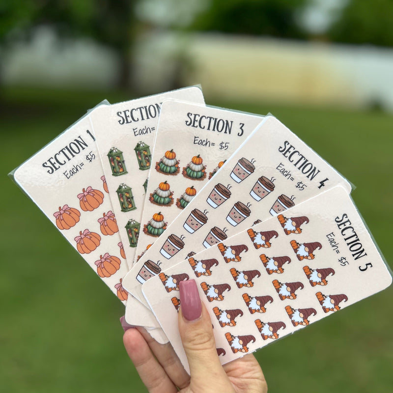 Hand holding four small cards with printed designs on a grassy background