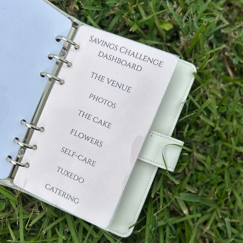 White planner with a list of wedding-related items on grass