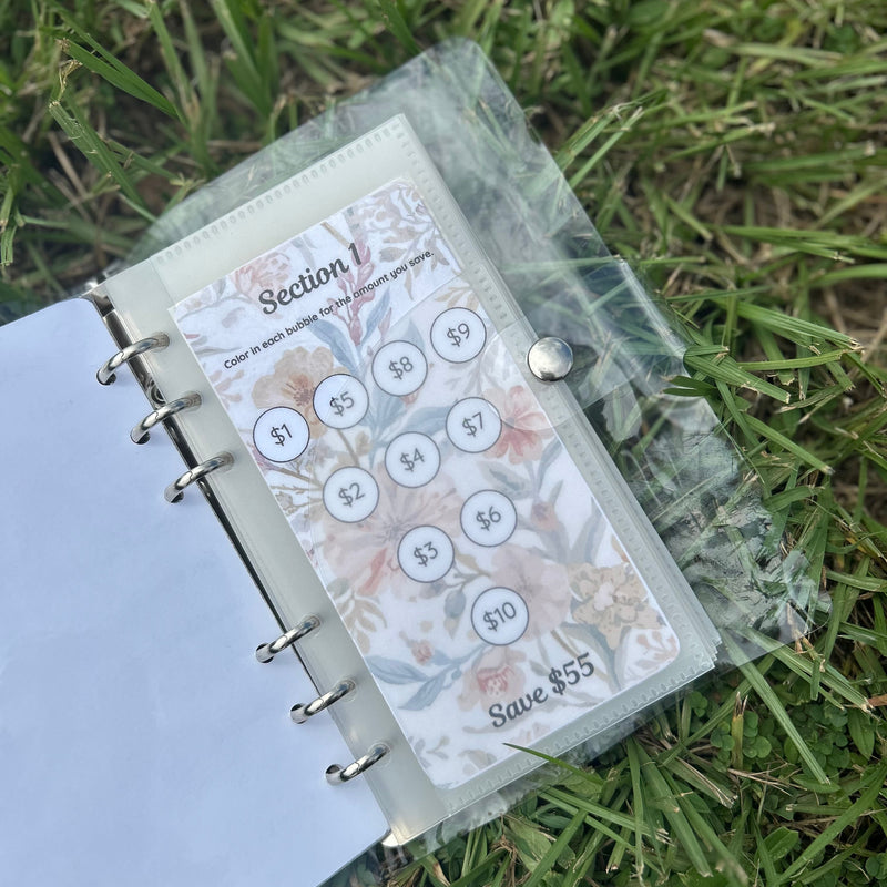 Planner with money-saving stickers on a grass background