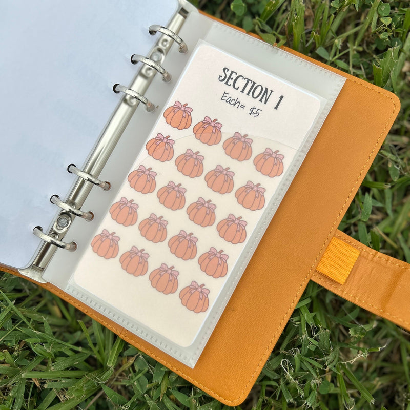 Notebook with a sheet of pumpkin-themed stickers on grass